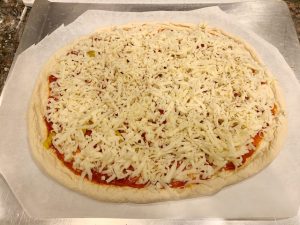 Pepperoni pizza with sliced banana peppers ready for grilling.