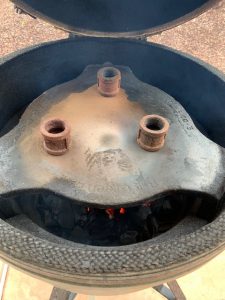 Big Green Egg plate setter legs down with pipe fittings on top to elevate pizza stone.